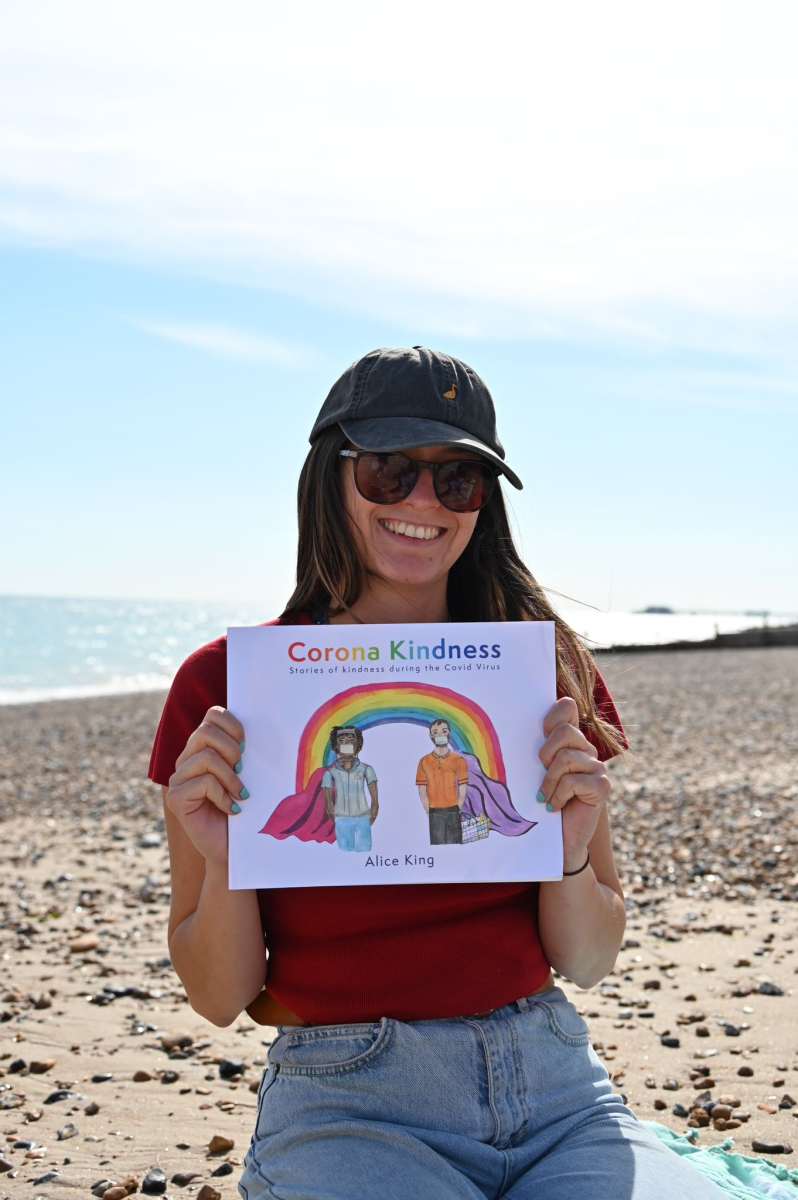 The author with her Corona Kindness book on a beach